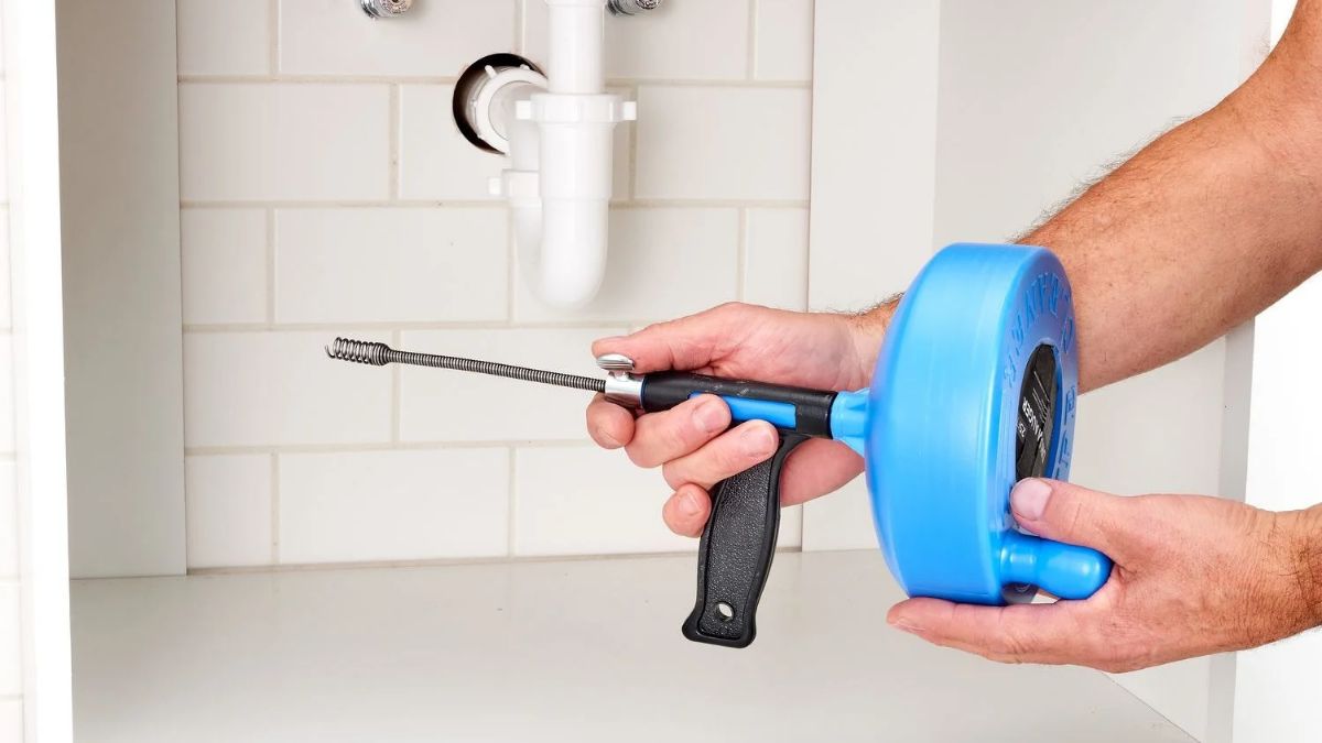 Plumber using a drain snake to clear a clogged drain in Lancaster, CA