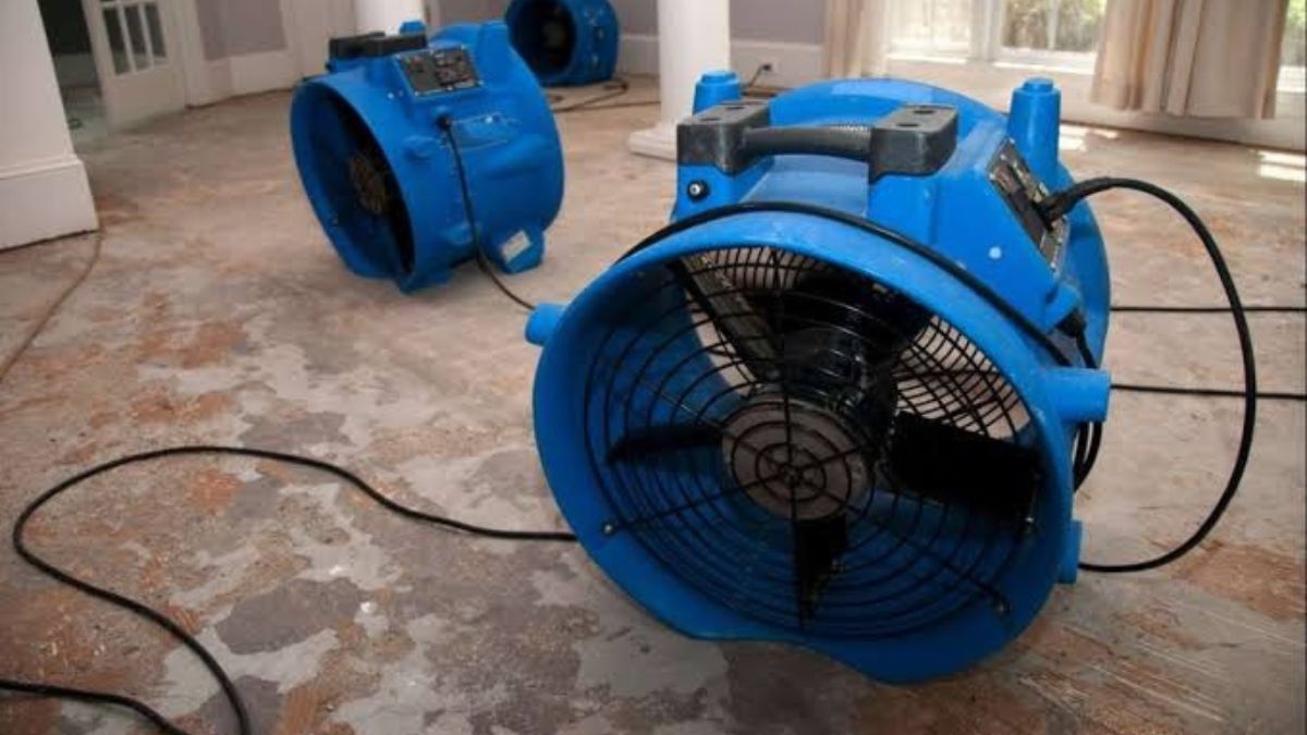 Water damage restoration technician drying a flooded room in a Lancaster, CA home